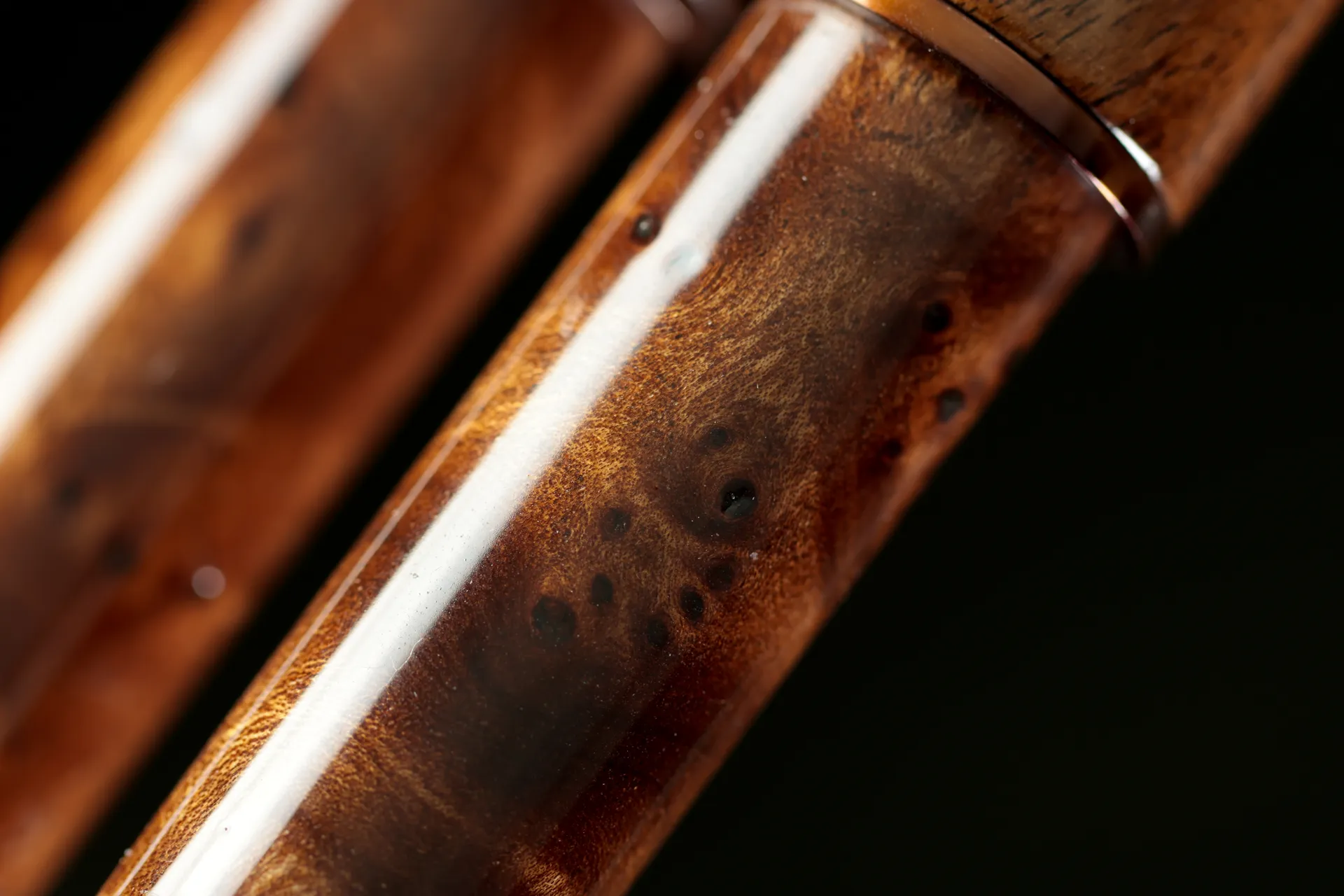 Image rapprochée de la poignée d'une canne feeder carpe, mettant en valeur la beauté naturelle du noyer de Creuse et les motifs uniques de la loupe d'orme, pour une esthétique raffinée.